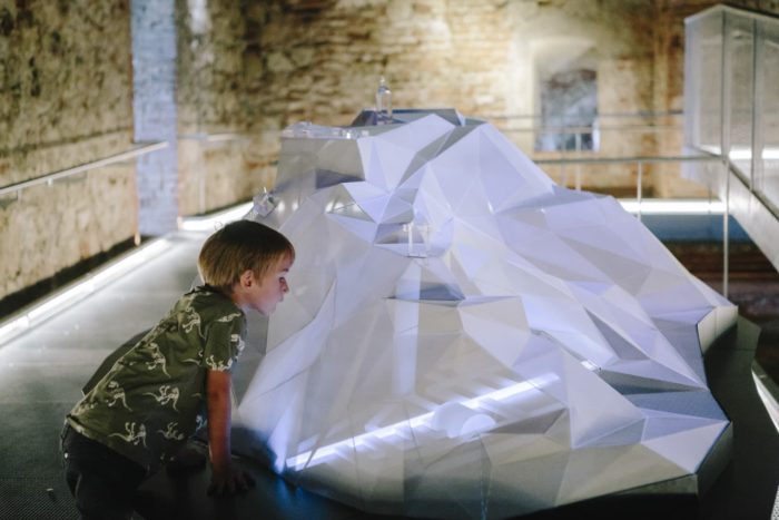 Ein kleiner Junge betrachtet das Schlossbermodell in der Kasematte, das das beleuchtete Stollensystem im inneren des Berges zeigt.