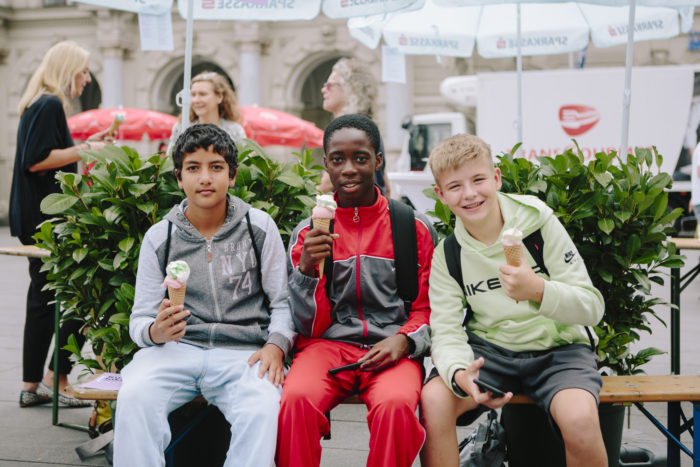 Drei Jugendliche sitzen nebeneinander und halten jeweils ein Eis in der Hand.