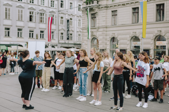 Eine Gruppe von Jugendlichen in Sommerkleidung steht in einer Reihe für eine Tanz-Aufführung