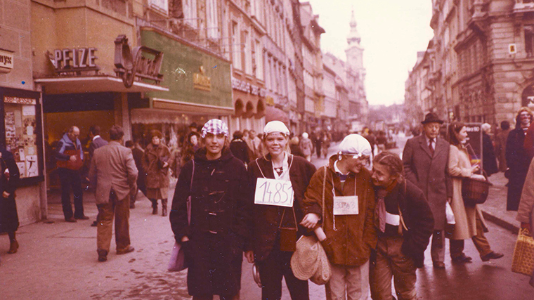 Drei junge Frauen in Verkleidung posieren in der Herrengasse nebeneinander für ein Foto. Im Hintergrund sind Menschen zu sehen, die zum Teil auch verkleidet sind.